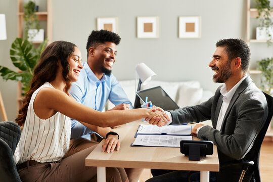 Young couple makes a deal with an agent in the office and does handshake