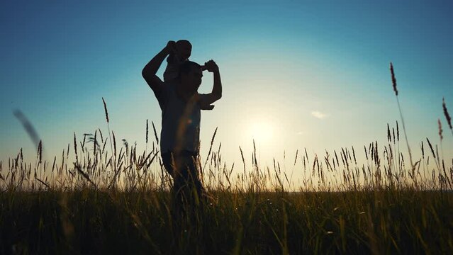 father and son in the park. father's day silhouette happy family child dream concept. father carries his son on his back. dad walk with lifestyle his son in nature in the park silhouette at sunset