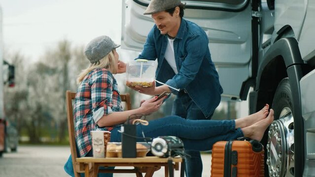Couple-in love truck drivers enjoy a break having lunch outdoors next to the truck in the parking lot