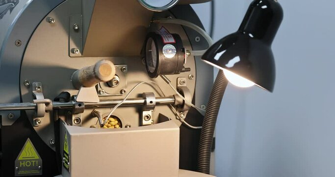 Control window of coffee roasting oven where you can see coffee beans of that are still raw.