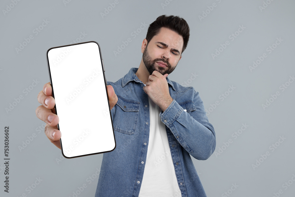 Aufkleber man holding smartphone with empty screen on grey background