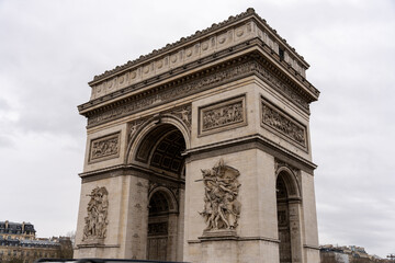 The Arc de Triomphe is a large, white arch with intricate carvings and statues