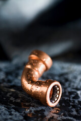 tubo de cobre curvado con gotas de agua sobre fondo negro