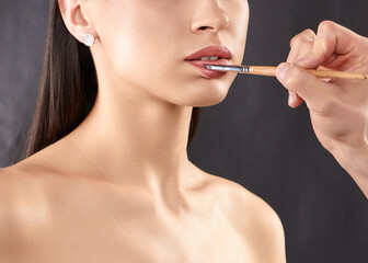 Fototapeta premium women paint their lips with a brush for a perfect lip contour