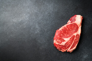 Beef steak. Ribeye steak raw meat on black. Top view with copy space.