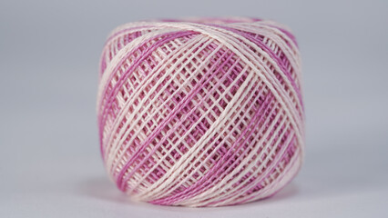 Ball of yarn for embroidery on a white, purple  variegated background close up, Pearl cotton threads.