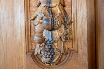 A carved wooden piece with fruit and leaves on it