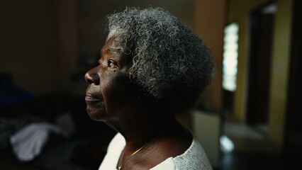 Close-up face of a Senior African American woman staring at window indoors in solitude. One...
