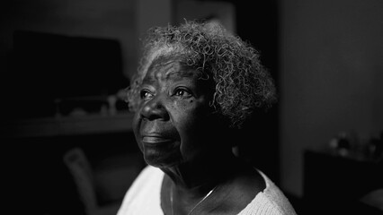 One introspective black senior woman in solitude at home in black and white. Monochromatic close-up...