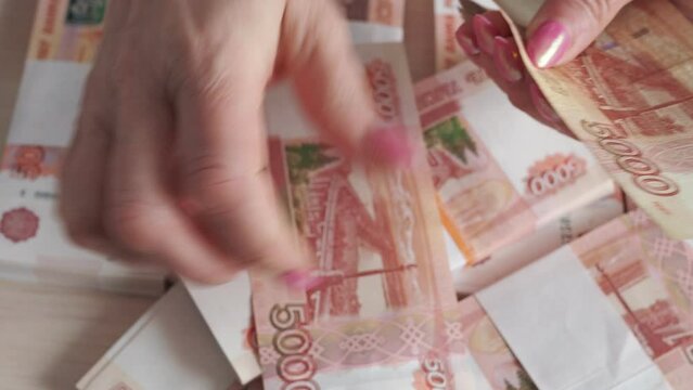 A female businesswoman recalculates banknotes, Russian rubles with a face value of 5000. Close-up.