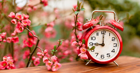 Flowers and red alarm clock. Spring forward, springtime or daylight savings time background. - 753057041