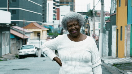 Portrait of a South American older lady standing in urban city street. African American 80s woman posing for camera outside