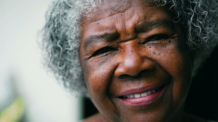 Portrait of a wrinkled jofyl wise senior African American woman in her 80s looking at camera. Warm...