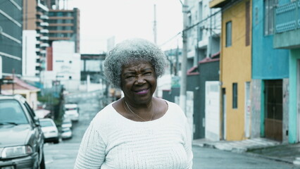 South American Senior black lady standing in city outside smiling at camera. 80s older person with...