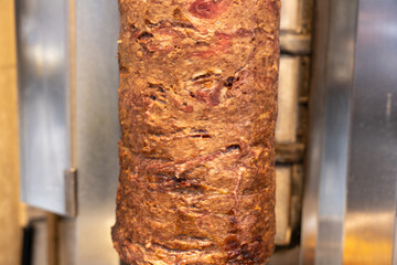 A long, brown roll of meat is being cooked on a grill