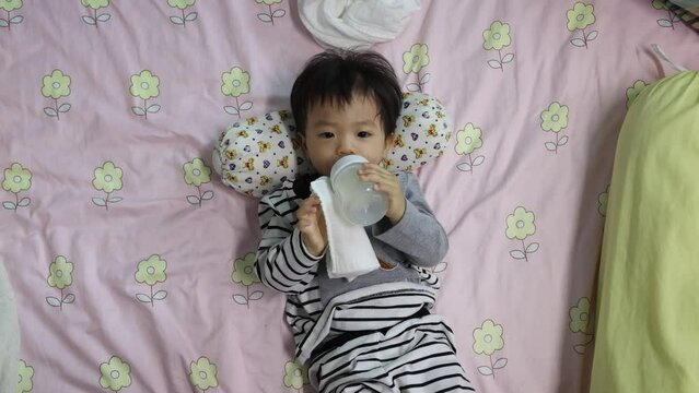 Asian Chinese baby boy drinking milk with holding milk bottle by him self.