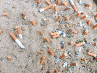 cigarette buttes in an ashtray filled with sand - obrazy, fototapety, plakaty