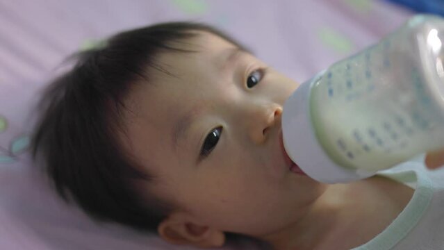 Asian Chinese baby boy drinking milk with holding milk bottle by him self.