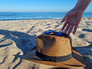 Travel concept, a woman picking up a hat in the sand