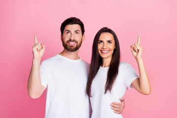 Photo portrait of attractive young couple hugging point look up empty space dressed stylish white clothes isolated on pink color background