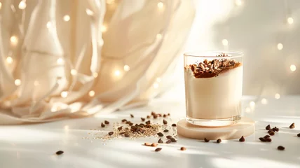 Tuinposter Cocoa on sesame milk with date paste and bran in glass. On empty white table with lights. Delicious natural cocoa drink with grated chocolate and milk in a glass. Side view, copy space. Recipe, menu © Dina Photo Stories