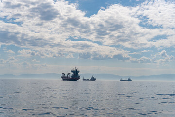 A large ship is sailing in the ocean with a few smaller boats behind it