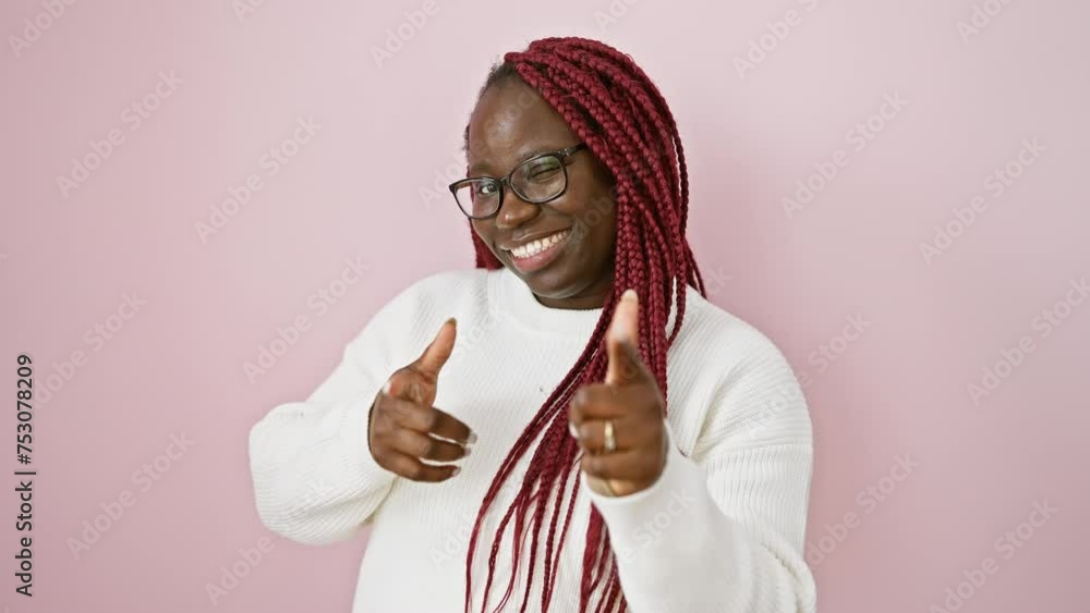 Sticker cheerful woman with braids pointing at camera against pink wall