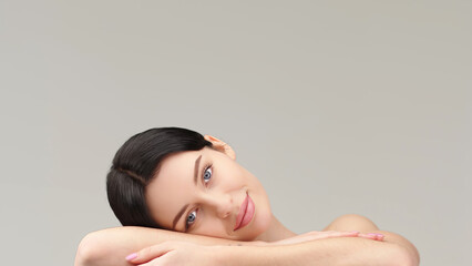 Fototapeta premium beautiful, young model rests her head on her hand, lying down and looking at the camera. The concept of healthy skin and female beauty, cosmetology services.