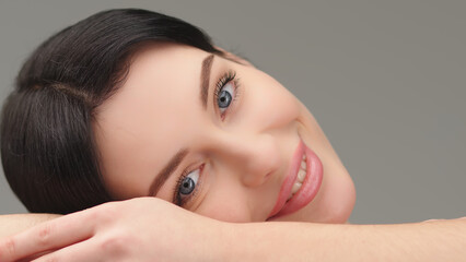 Obraz premium beautiful, young model rests her head on her hand, lying down and looking at the camera. The concept of healthy skin and female beauty, cosmetology services.