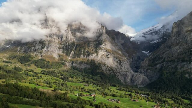 Drone footage of the Alps near Grindelwald, Switzerland with fog and blue sky on sunny day