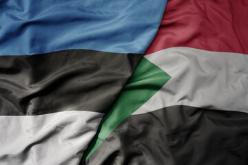 big waving national colorful flag of sudan and national flag of estonia.