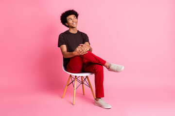 Full body size photo of young relaxed guy sitting on stool comfortable pose dreamy looking novelty isolated over pink color background
