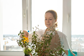 Indoor gardening, woman with spray bottle, plant care, home greenery.
