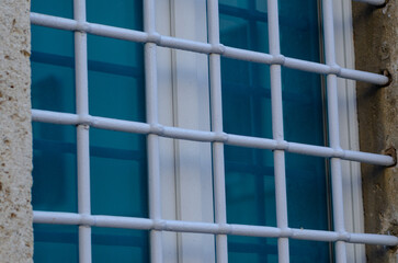 window with grate, building with old windows and white grates. new and modern glass on an ancient...