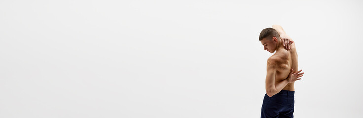 Obraz premium Back pain. Rear view of shirtless young man with relief strong back isolated over white background. Concept of sportive lifestyle, body and heath care, youth. Banner. Empty space to insert text, ad