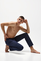 Fototapeta premium Handsome young man with short brunette hair, shirtless, muscular, relief body posing in jeans isolated over white studio background. Concept of sportive lifestyle, body and heath care, youth