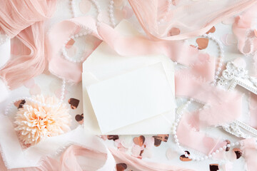Card near pink decorations, hearts and silk ribbons on white table top view, mockup