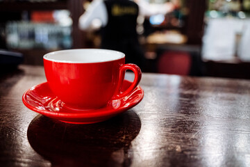 Tableware set featuring a red cup and saucer on a wooden table