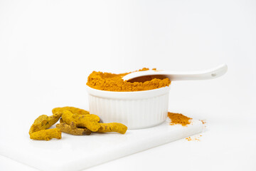 Turmeric powder, spices and dried root on white background.