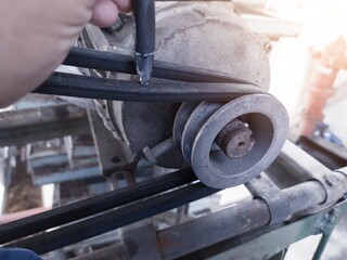 Checking the tenssion of the belt pulley using hand estimates.
