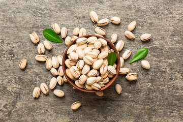 Fresh healthy Pistachios in bowl on colored table background. Top view Healthy eating concept....