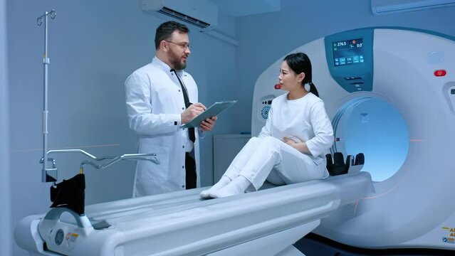 Doctor talking to patient before undergoing MRI. Patient explaining symptoms to doctor. Doctor making notes about patient well being. Magnetic resonance imaging. Doctor and patient.