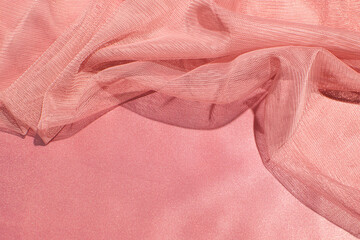 Peach pink satin and light mesh fabric carelessly crumpled, creative copy space.