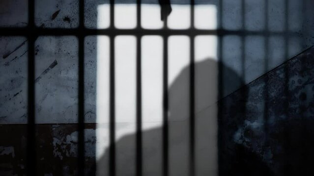 Silhouette of a man in prison: wearing headphones, happily dancing to the music, confined behind bars, his image cast upon a weathered wall.
