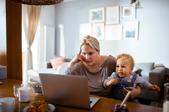 Stressed mother with toddler trying to work from home
