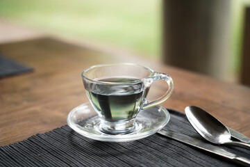 Blue tea is served in a nice glass cup at the breakfast table.           