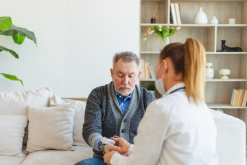 Obraz premium Female doctor senior man taking his blood pressure in doctor office or at home. Old man patient and doctor have consultation in hospital room. Medicine healthcare medical checkup. Visit to doctor