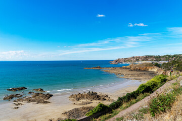 Obraz premium Depuis les hauteurs des falaises, contemplez la plage des Côtes d'Armor, où le sable rencontre les sillons rocheux, offrant une vue à couper le souffle sur l'union majestueuse de la terre et de la mer