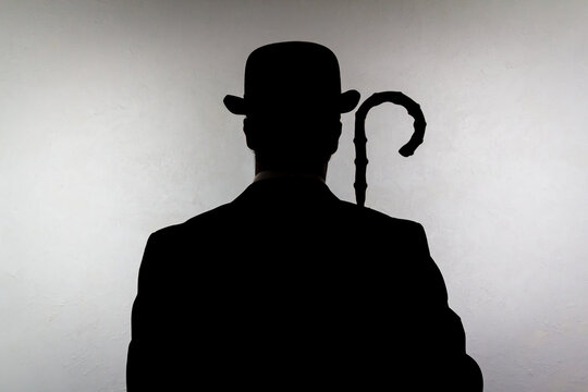 Backlit Portrait of English Gentleman in Bowler Hat Holding Umbrella. Vintage Style of British Spy Hero and Crime Fighter.