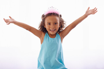 Little girl, excited and portrait on white background, princess crown and sweet for birthday and...